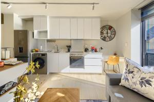 a kitchen and living room with white cabinets and a couch at Tokyo Studio with Balcony - Book 4 & Get 5th Night FREE in Cape Town