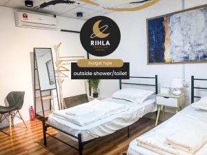 2 Betten in einem Zimmer mit einem Schild, das Rila Outlet Show zeigt in der Unterkunft Rihla Bandar Utama in Gua Musang