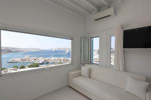 a living room with a white couch and a large window at Adikri Villas & Suites in Tourlos