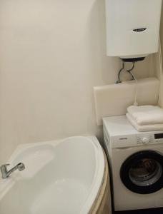 ein kleines Bad mit einer Waschmaschine und einem Waschbecken in der Unterkunft ApartamentFortuna1 in Palanga