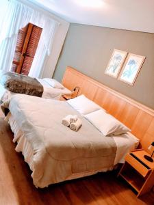 1 dormitorio con 2 camas y toallas. en Pousada Condado Brasileiro, en Campos do Jordão
