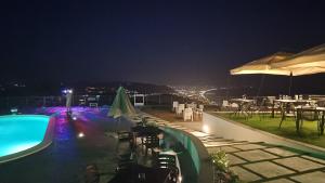 una piscina notturna con tavoli e ombrelloni di Appartamento Emma con Piscina - Vista Mare"Tenuta Croce" a Salerno