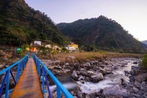 a bridge over a river next to a mountain at goSTOPS Dehradun, Maldevta in Dehradun