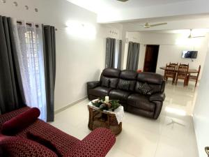 Una sala de estar con un sofá de cuero y una mesa. en PAZHOOR RESIDENCY HOME STAY 4BHK Deluxe, en Trivandrum