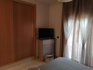 a bedroom with a bed and a television on a dresser at Bajo puerta de Alcazaba in Retamar