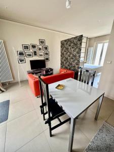 ein Wohnzimmer mit einem weißen Tisch und einem roten Sofa in der Unterkunft Piccolo Loft in centro Asti in Asti