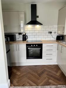 a kitchen with white cabinets and a black oven at The Lookout@brighouse in Brighouse