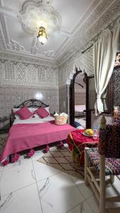 1 dormitorio con 1 cama grande con manta rosa en Riad Hayat, en Marrakech
