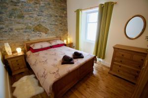 1 dormitorio con 1 cama con pared de piedra en Tigh Muileann, en Killin