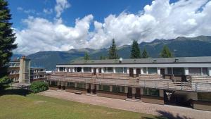 a large building with mountains in the background at Residence Copai in Mezzana