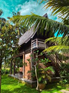 a house with a palm tree in front of it at Nunu Bali Eco Friendly Retreat in Canggu