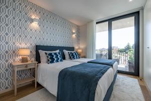 een slaapkamer met een bed en een groot raam bij BONFIM LIVING - Great location, al fresco dining and free private parking in Porto