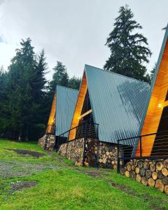una casa con tetto verde e un mucchio di tronchi di Collodi Cottages a Tba