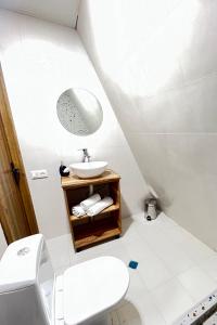 La salle de bains blanche est pourvue d'un lavabo et de toilettes. dans l'établissement Collodi Cottages, à Tba