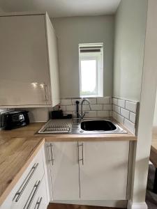 a kitchen with white cabinets and a sink at The Lookout@brighouse in Brighouse