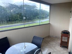 a table and chairs in a room with a large window at 4 Aps baratos, confortáveis, completos e com garagem insta thiagojacomo in Goiânia