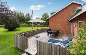 a wooden deck with a table and an umbrella at Stunning Home In Hjer With 3 Bedrooms And Wifi in Højer