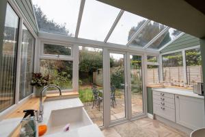 a kitchen with a conservatory with a sink and windows at Loke Cottage - Winchelsea Nr Rye in Winchelsea