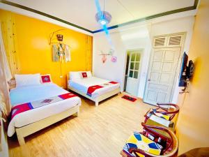 2 Betten in einem Zimmer mit gelben Wänden und einer Tür in der Unterkunft YoLoHome in Sa Pa