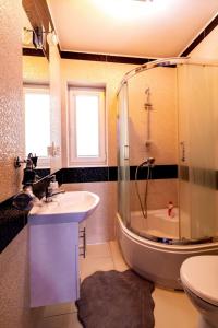 La salle de bains est pourvue d'un lavabo, d'une douche et d'une baignoire. dans l'établissement Jagodowy Domek, à Święta Katarzyna