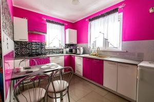 a kitchen with pink walls and a table and chairs at Jagodowy Domek in Święta Katarzyna