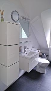 uma casa de banho branca com um lavatório e um WC em Ferienwohnung Adrián em Saarbrücken