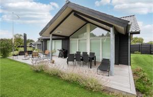 Casa con terraza de madera con mesa y sillas en Awesome Home In Karrebksminde With Kitchen, en Karrebæksminde