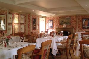 een restaurant met witte tafels en stoelen en een open haard bij The Royal Hotel in Comrie