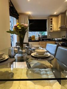 a kitchen with a glass table with a vase of flowers at Cozy 2 bed flat ! Amazing bath! in London