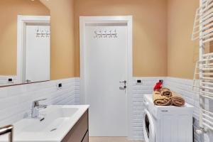 La salle de bains est pourvue d'un lavabo blanc et d'un lave-linge. dans l'établissement Alessia's Flat - Naviglio Grande 2, à Buccinasco