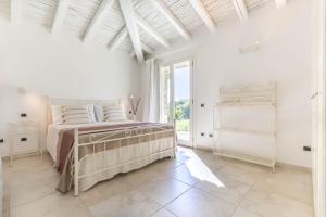 a white bedroom with a bed and a window at Villa Mandorlo a soli 500 mt dal mare con piscina privata e vista mare in Costa Rei +36 photos