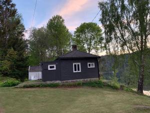 ein kleines schwarzes Haus mitten auf einem Feld in der Unterkunft Solrik hytte med tilgang til brygge og stor hage in Risør