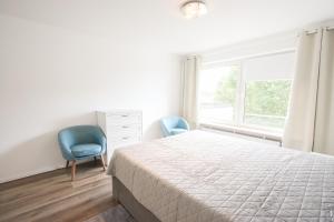 1 Schlafzimmer mit einem Bett, 2 Stühlen und einem Fenster in der Unterkunft Modernes und zentrales 4 Zimmer Apartment in Hamburg