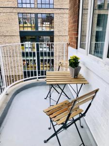 ロンドンにあるCity location- 2 bedroom apartmentのベンチ、テーブル、植物が置かれたバルコニー