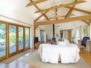 a bedroom with a large white bed and a living room at The Cottage at Hale Hill Farm, Pulborough in Pulborough