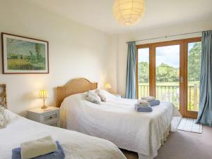 a bedroom with two beds and a window with a balcony at The Cottage at Hale Hill Farm, Pulborough in Pulborough