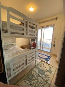 a bedroom with a white bunk bed and a large window at porto marina north coast alamein in El Alamein