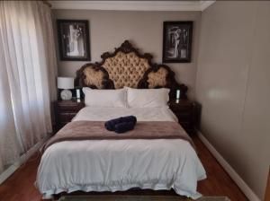 Schlafzimmer mit einem großen Bett mit einem Kopfteil aus Holz in der Unterkunft La Cordier in Kroonstad