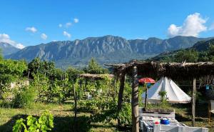 a farm with a tent and mountains in the background at Ljubicani Village Glamping in Virpazar