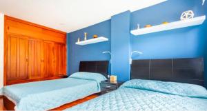 two beds in a room with blue walls at Nice room in Chapinero alto in Bogotá