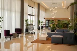 グァイーラにあるTrento Hotel Guaíra by Unnaのロビー(ソファ、椅子、植物付)