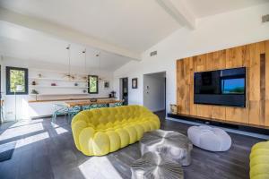uma sala de estar com um sofá amarelo e uma televisão em Villa du Couvent Version Maquis em Bonifacio