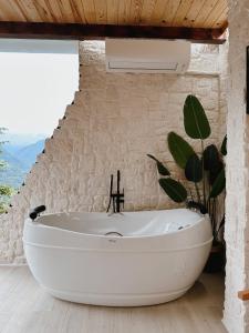 a bathroom with a large white tub in a stone wall at TAŞ MAHAL BUNGALOV in Çamlıhemşin