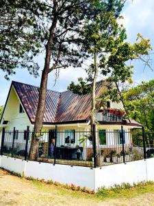 uma casa branca com um telhado de metal e uma cerca em Melia's House Baguio - Nature Home for Rent em Baguio