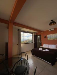 - une chambre avec un lit, une table et une fenêtre dans l'établissement Pousada Pouso e Prosa, à Lavras Novas