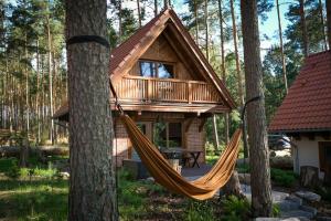 a hammock in front of a log cabin in the woods at Osada Swory domki w lesie nad jeziorem in Małe Swornegacie
