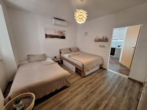 1 dormitorio con 2 camas y lámpara de araña en Apartma Pingo, en Koper