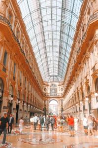 un gruppo di persone che camminano in un edificio con un soffitto di vetro di The Boutique Houses Milan - Galleria - With Private Parking a Milano
