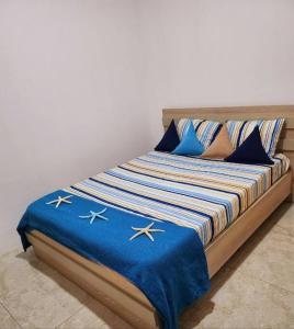 a bed with blue and white blankets and pillows at Kot Nu - Beach Themed Apartment - 3 mins walk from the sea in Flic-en-Flac