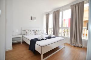 a white bedroom with a bed and windows at Perfect apartment for beach lovers, next to the sailing club in El Arenal